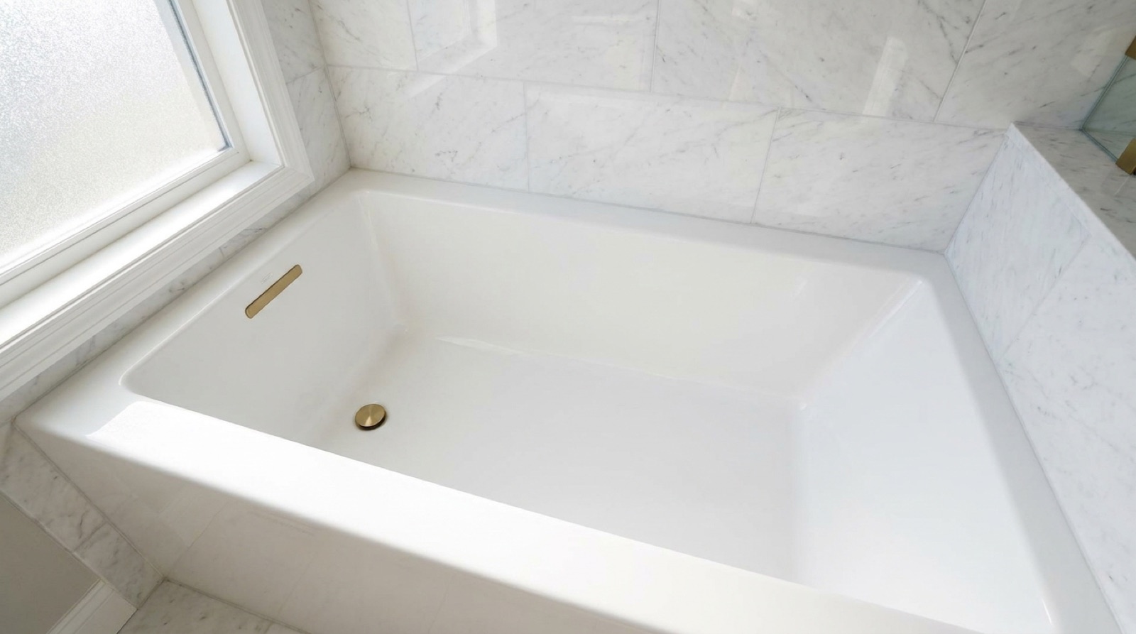Interior of a roomy white acrylic alcove bathtub with flat sides and a tile surround